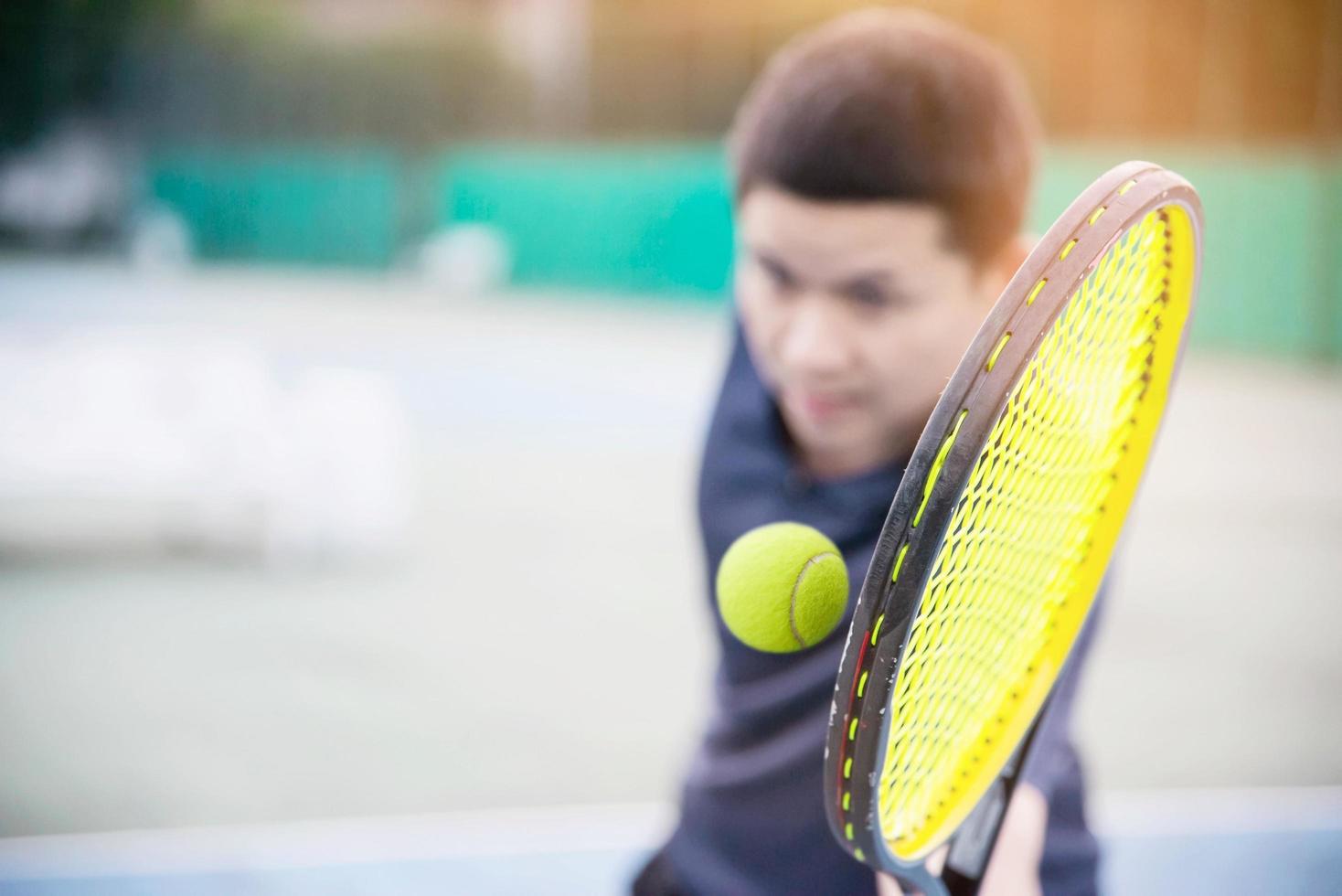 hombre que sostiene la raqueta a punto de golpear una pelota en la cancha de tenis - gente en el concepto de partido de tenis foto