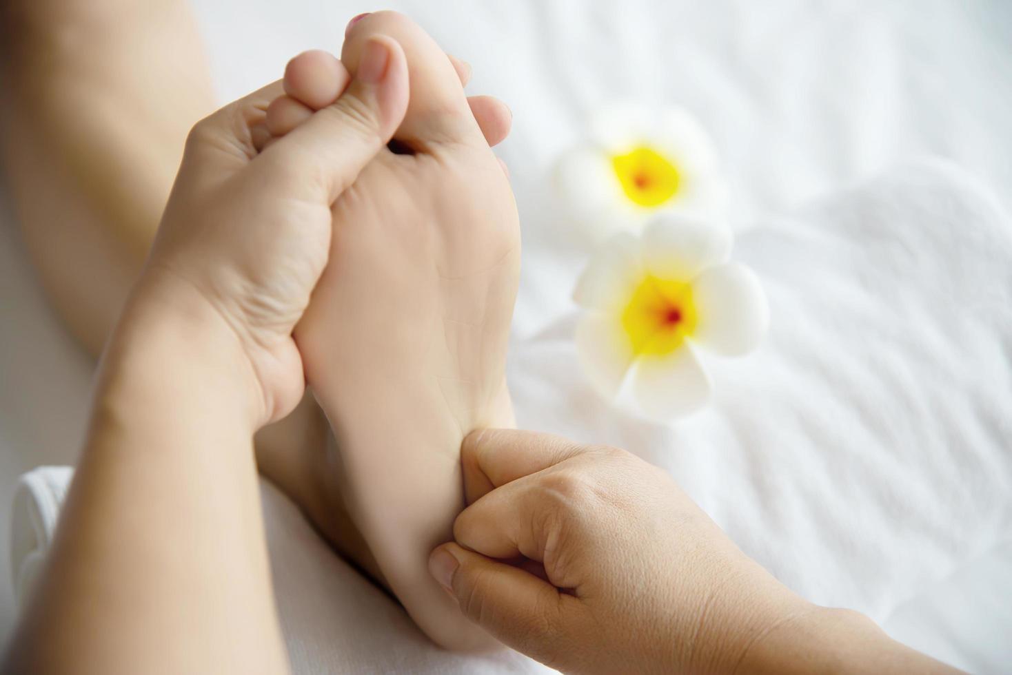 Woman receiving foot massage service from masseuse close up at hand and foot - relax in foot massage therapy service concept photo