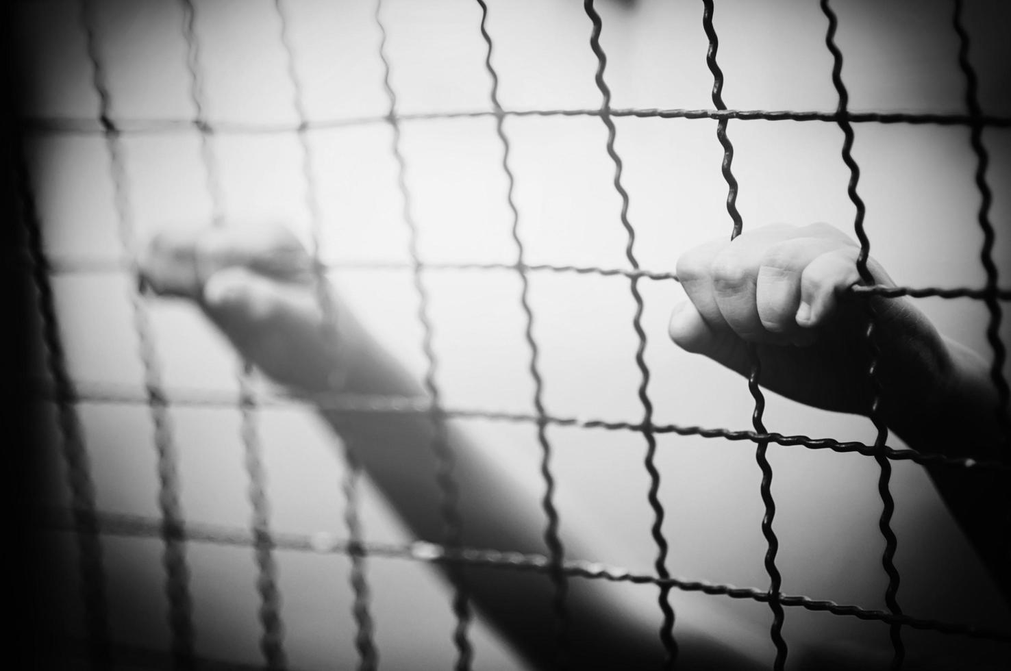 Dark portrait of a boy and holding steel screen or chain link fence - stressed sad child with no freedom concept photo