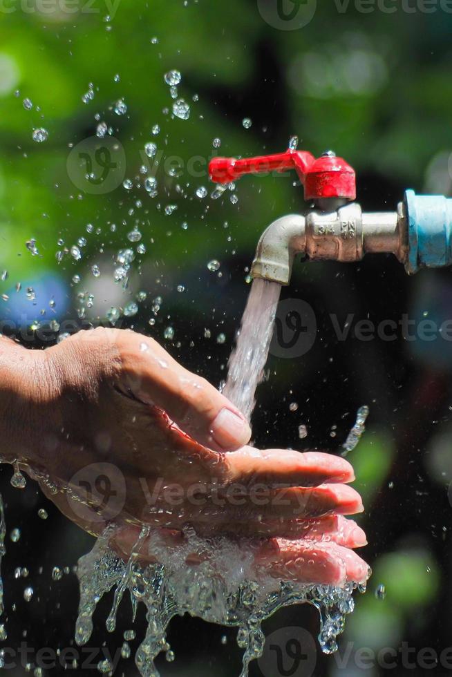 Water concept in everyday life. Hands supporting the water flowing from the faucet. water splashing from the tap photo