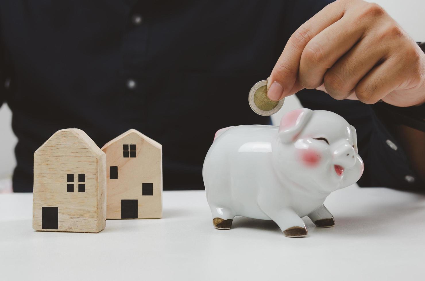 Hand holding coin saving piggy bank finance investment loan house. business economy home estate property concept. photo