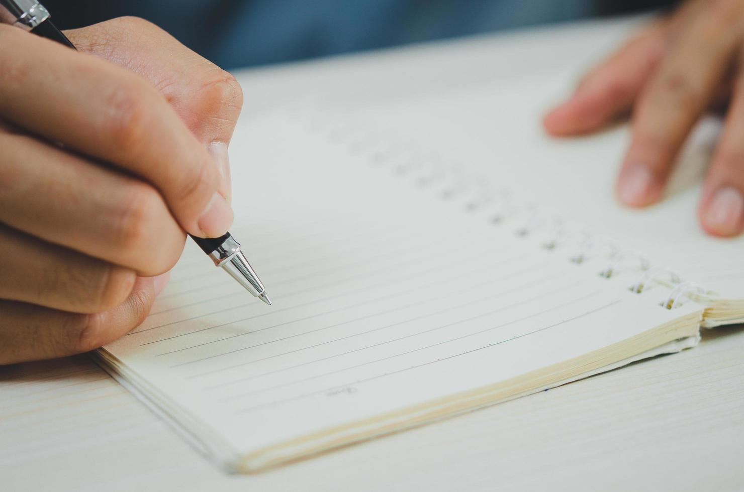 persona sosteniendo un bolígrafo escribiendo notas en un cuaderno. foto