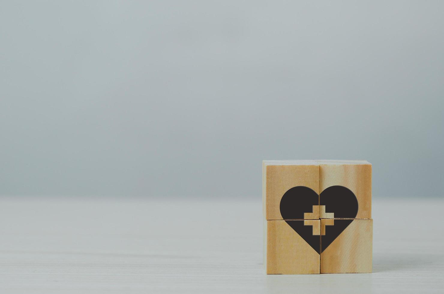 Wooden cube with health insurance icon on table background. photo