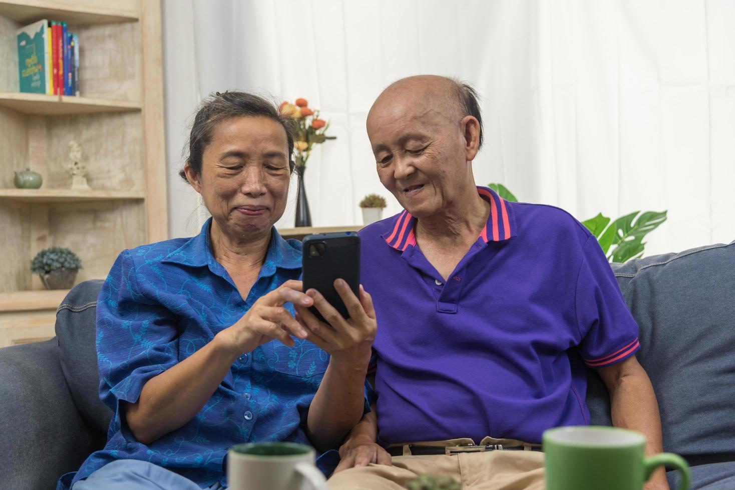 ancianos asiáticos que utilizan la tecnología de comunicación de Internet en línea de conexión de teléfono móvil en casa. foto