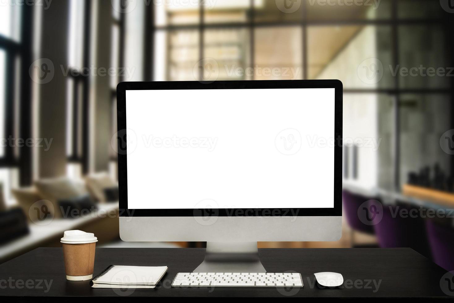 Computer monitor with white blank screen putting on white working desk with wireless mouse and keyboard over blurred vintage office photo