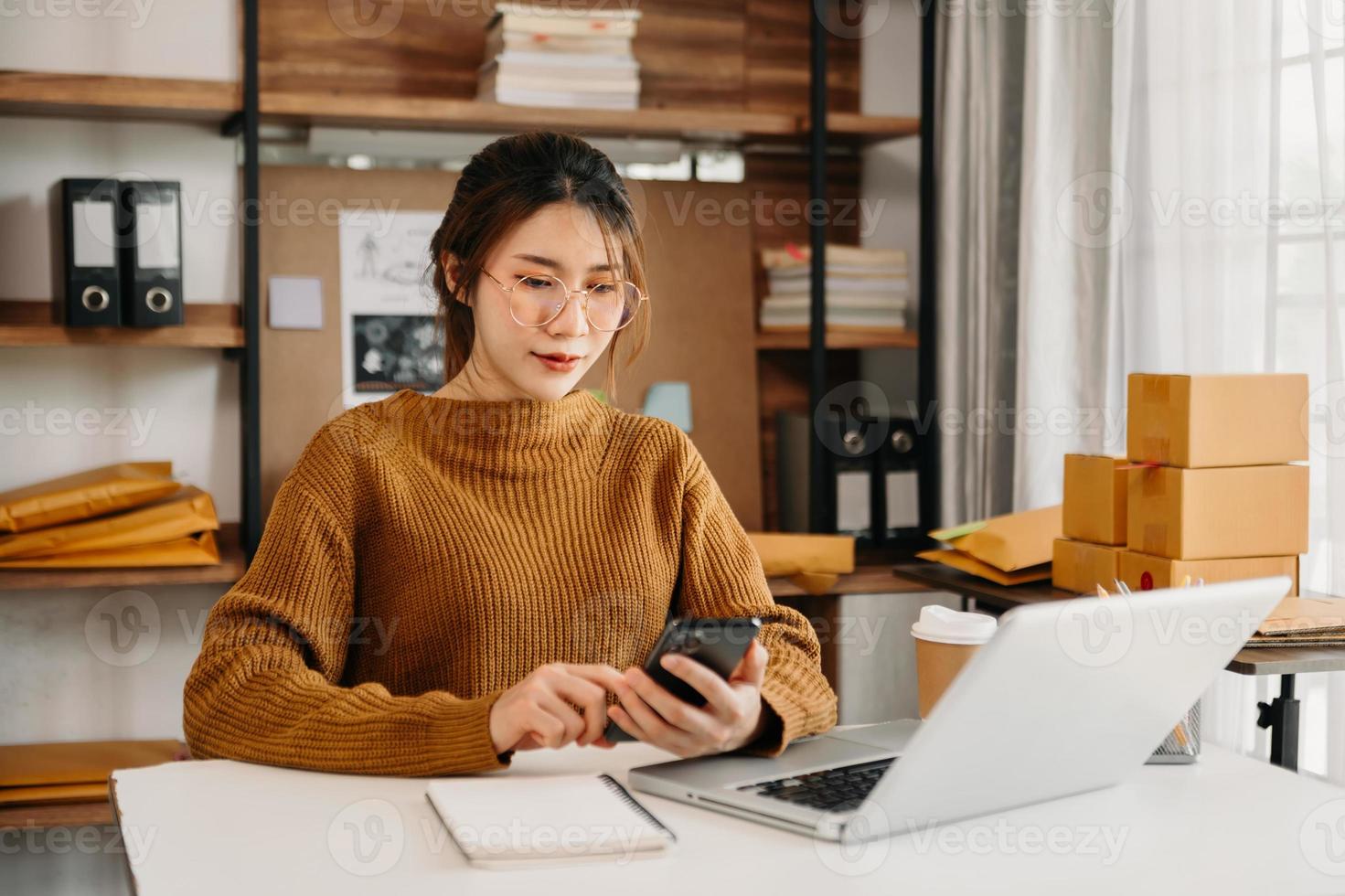 Asian woman SME working with a box at home the workplace.start-up small business owner, small business entrepreneur SME or freelance business online and delivery concept. photo