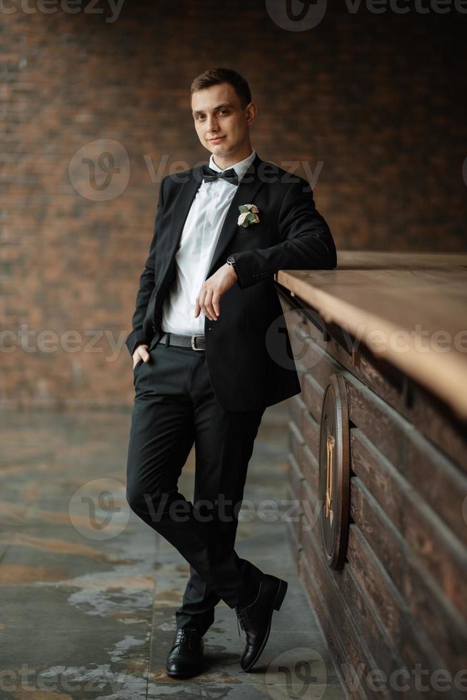 portrait of a young guy groom in a black suit photo