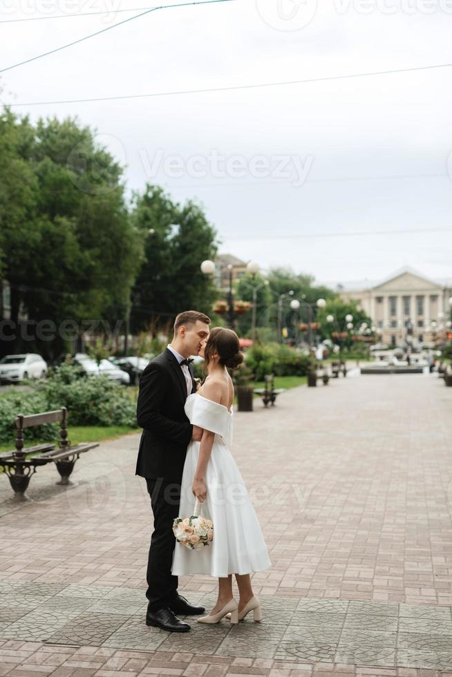 young couple bride and groom in a white short dress photo