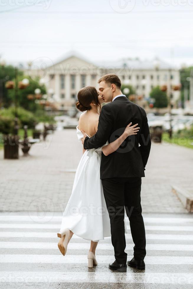 young couple bride and groom in a white short dress photo