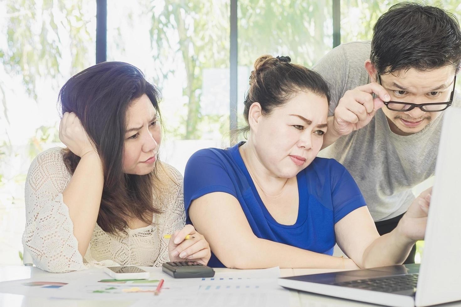 dos mujeres y un hombre están trabajando seriamente juntos en la oficina moderna foto