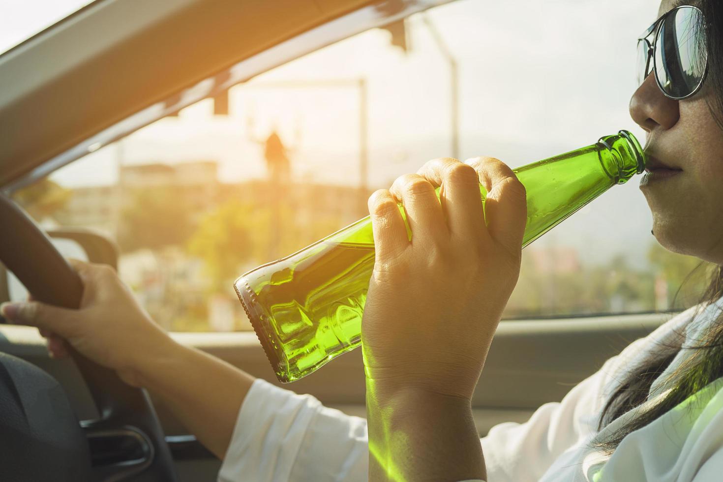 Woman drinking beer while driving a car photo