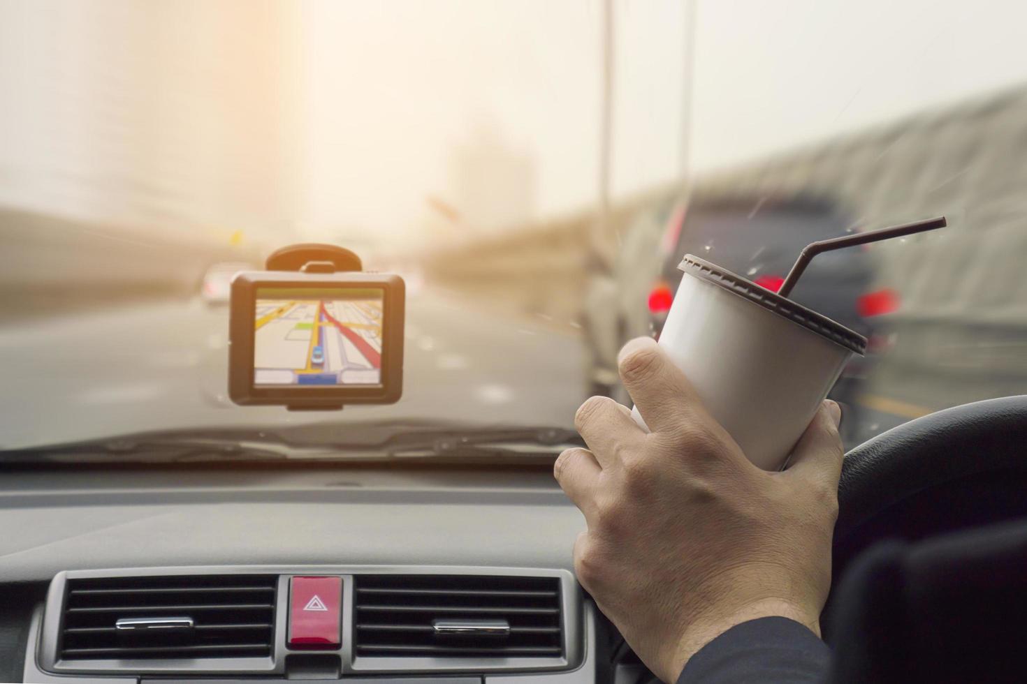 Man driving car using navigator and holding coffee cup photo