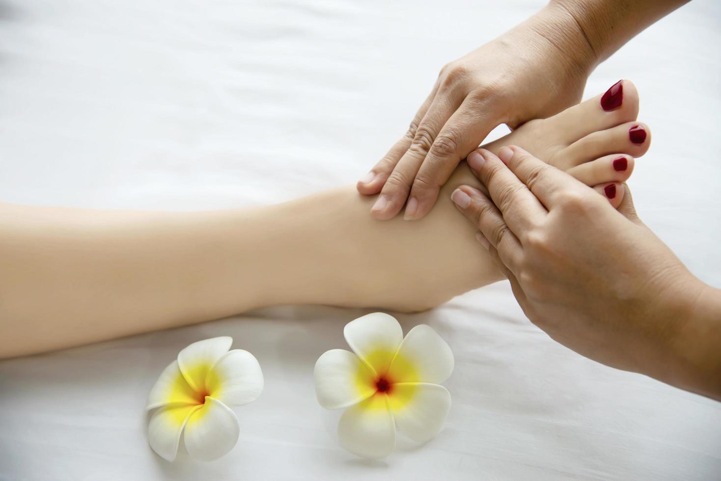 Woman receiving foot massage service from masseuse close up at hand and foot - relax in foot massage therapy service concept photo