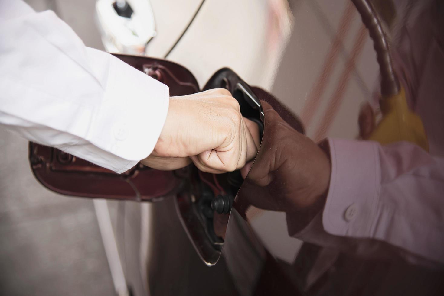 Man is putting NGV, Natural Gas Vehicle, head dispenser to a car at the gasoline station in Thailand photo