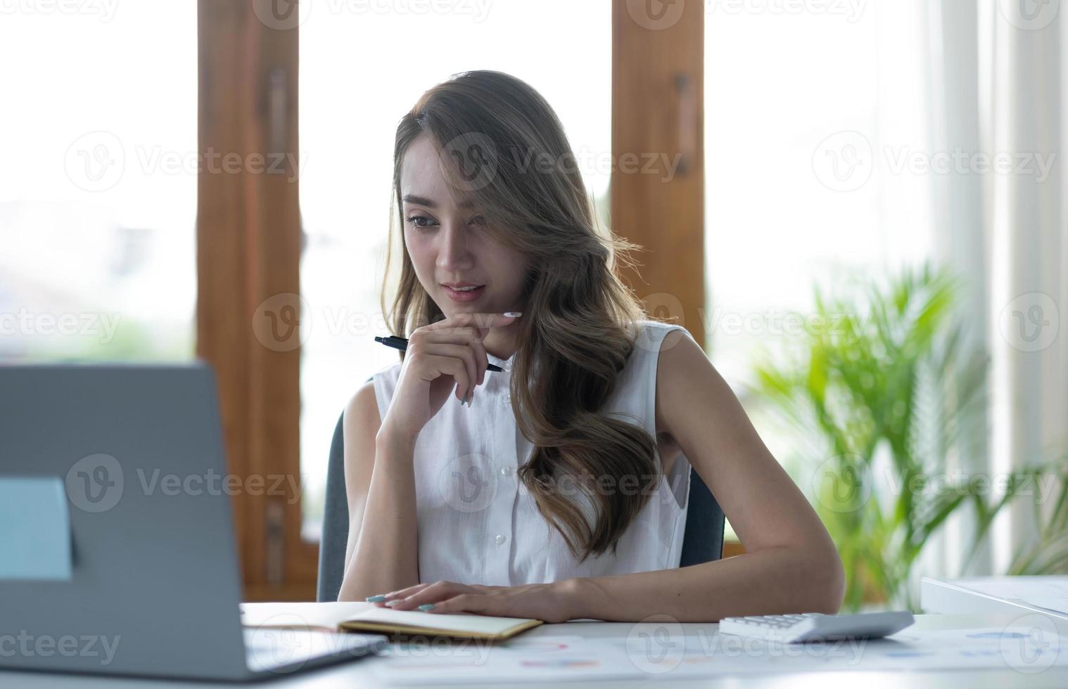 Portrait of Young Asian woman hand freelancer is working her job on computer tablet in modern office. Doing accounting analysis report real estate investment data, Financial and tax systems concept. photo