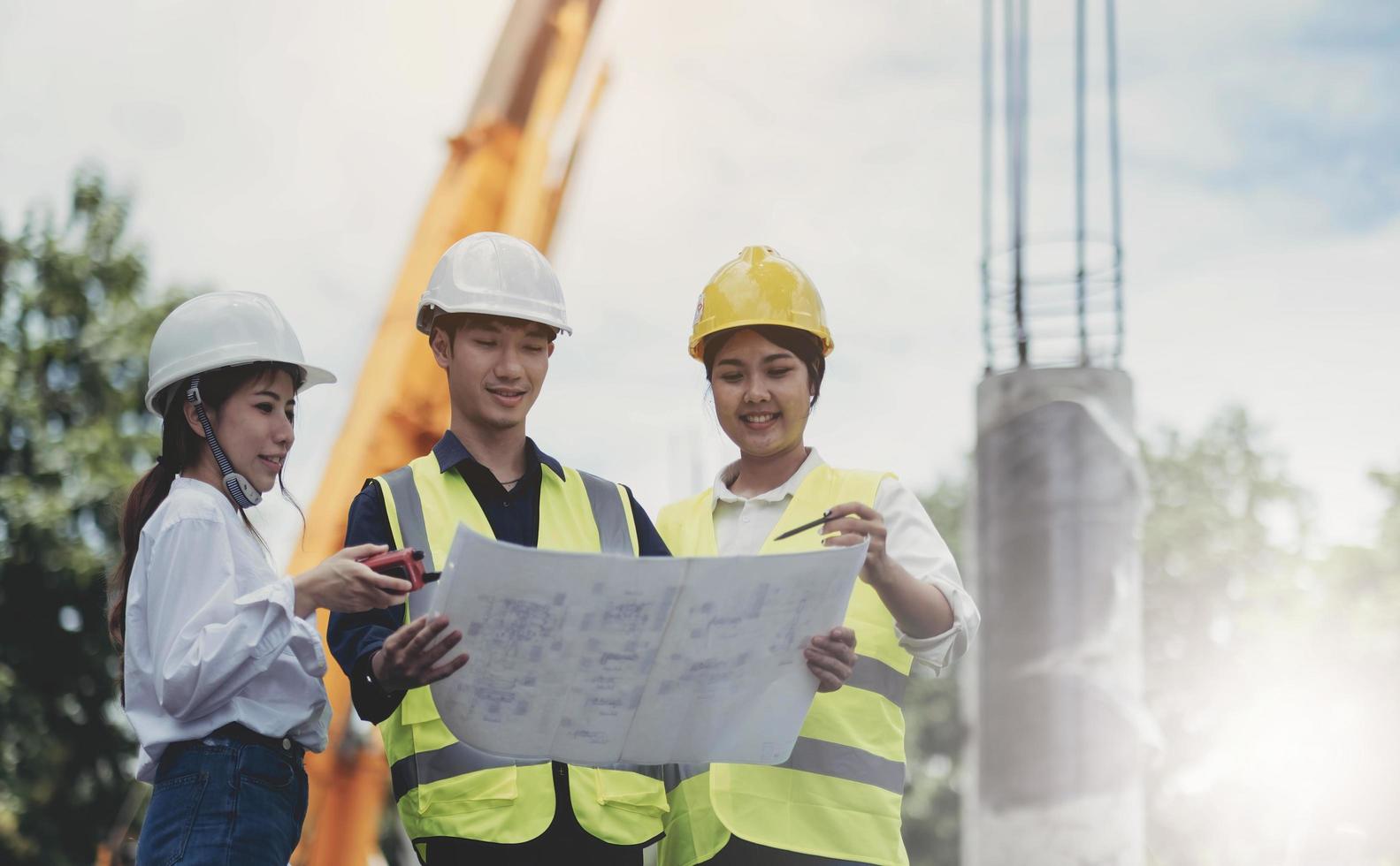 Three experts inspect commercial building construction sites and construction site holding blueprints photo