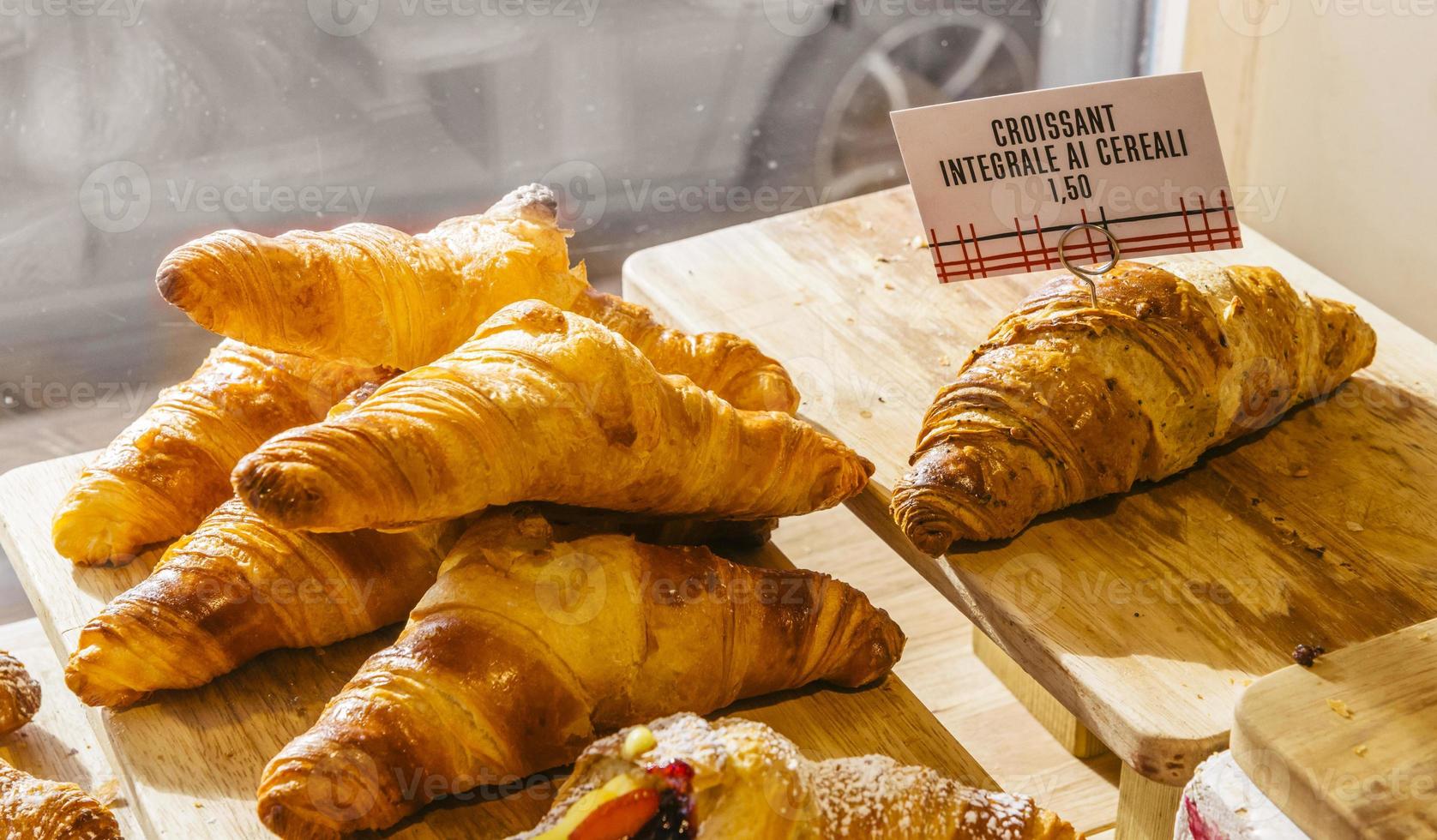 Various flavours of croissant or as in Italy their called brioche on display in a bakery in Milan, Italy with a price and sign - Albicocca means jam in Italian photo