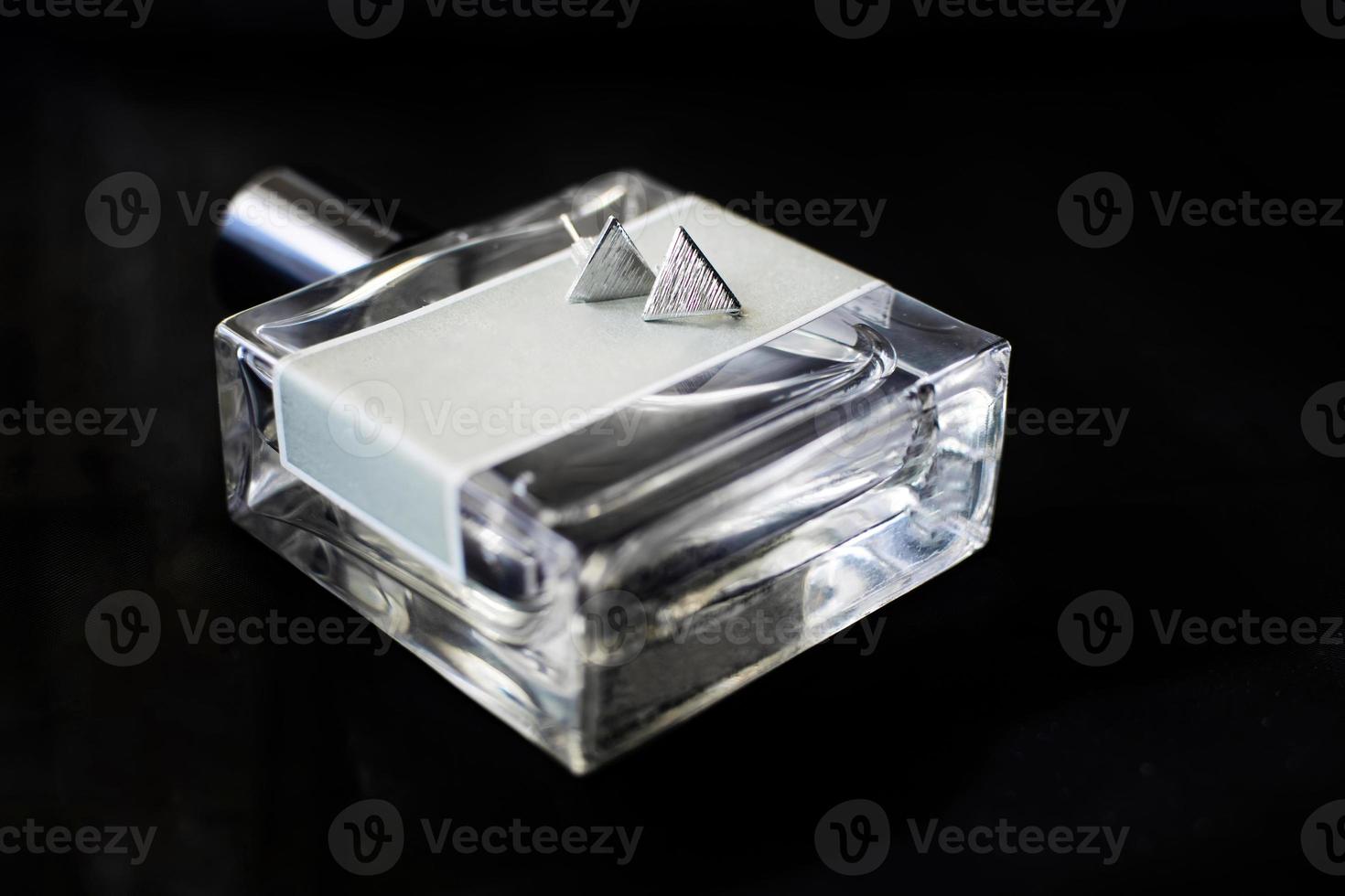 pendientes de plata en una botella de perfume de vidrio. concepto de boda. foto