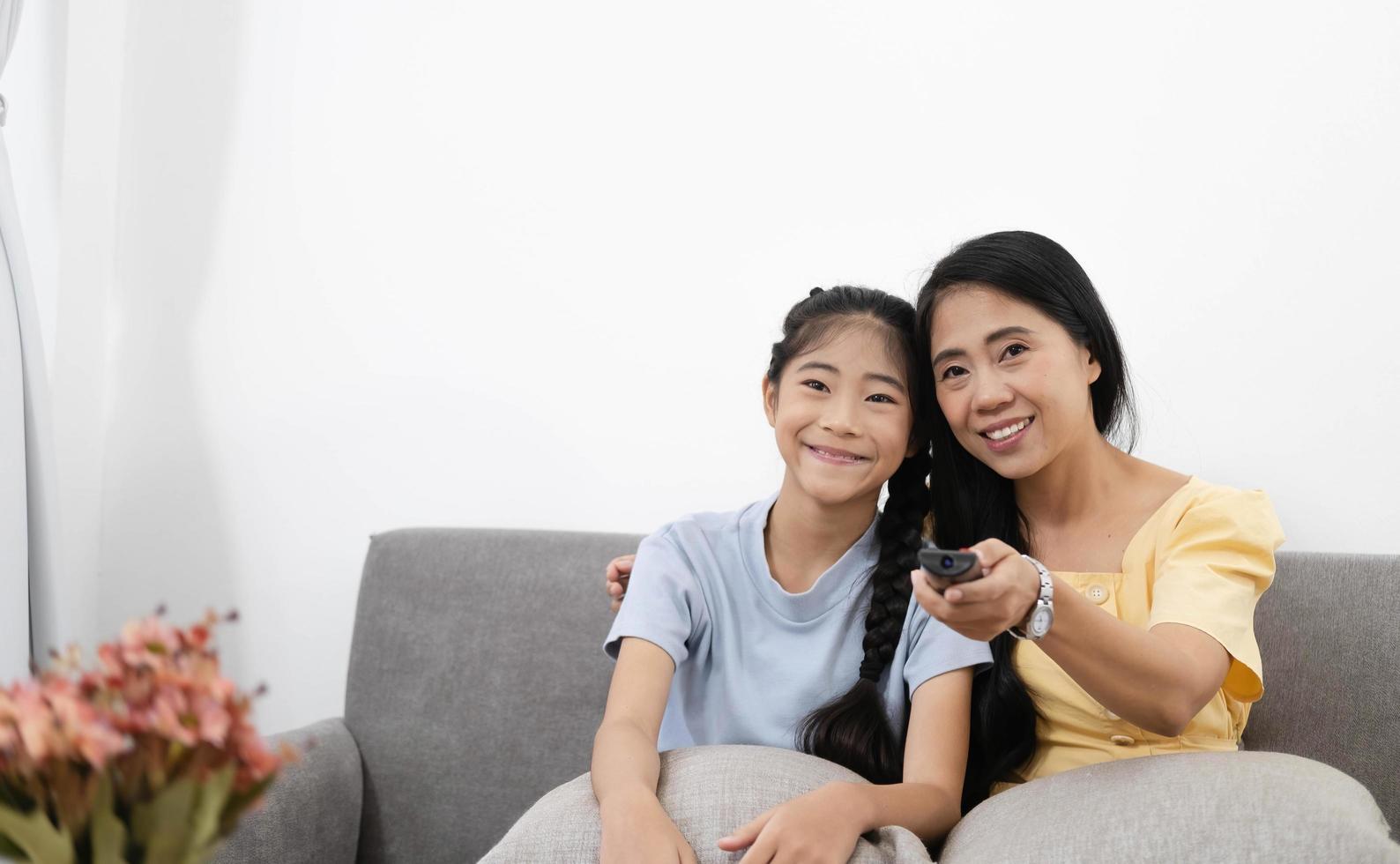 Happy asian parents sit on comfortable couch in living room with little kids watch TV enjoy home weekend enjoying movie photo