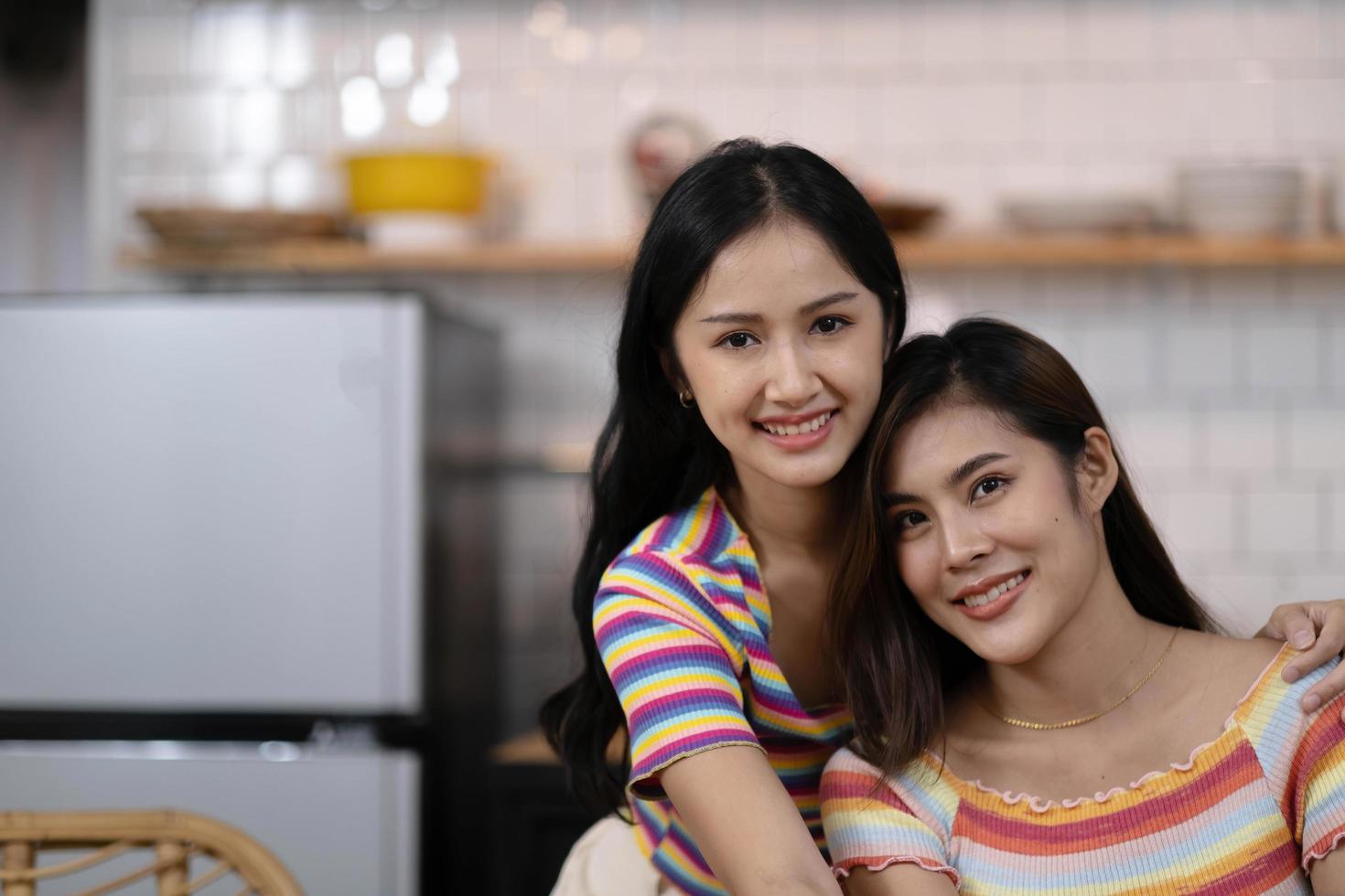 Portrait of a smiling young lesbian couple hugging each other while standing together at home photo