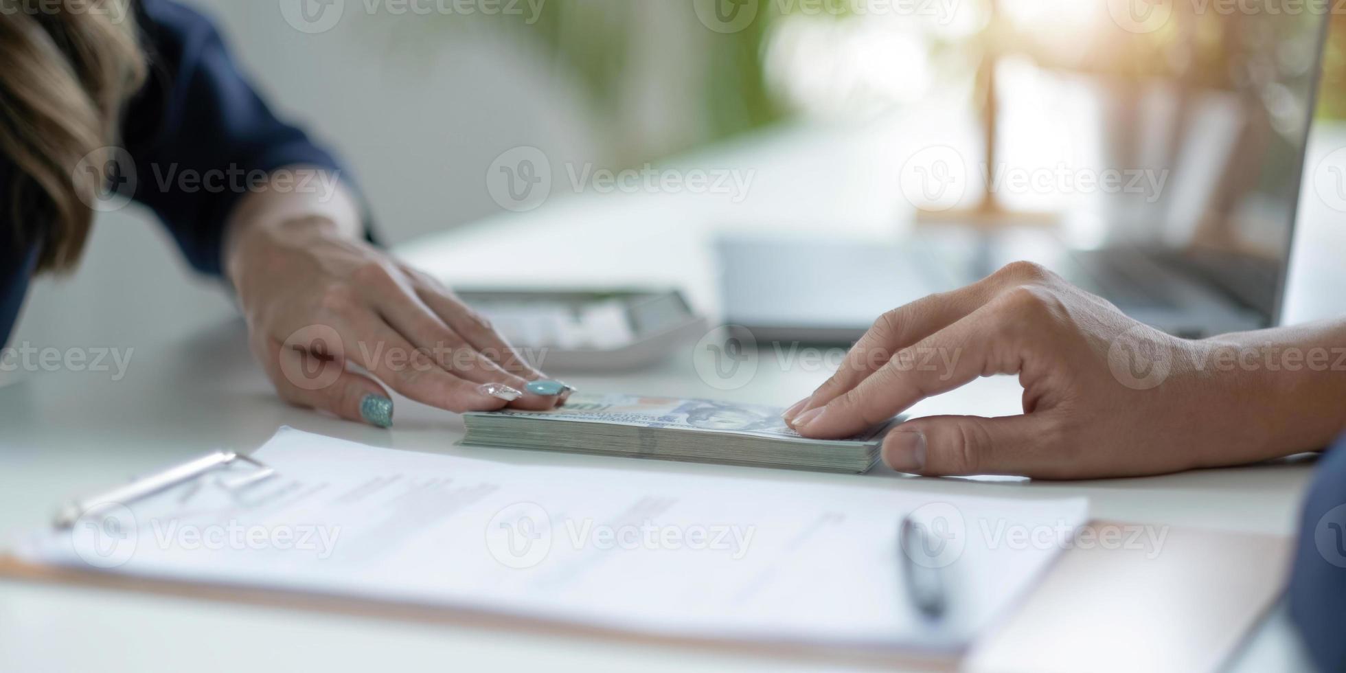 Businessman giving  of money, cash dollars to his partner over an office desk - loan, payment and bribery concepts photo