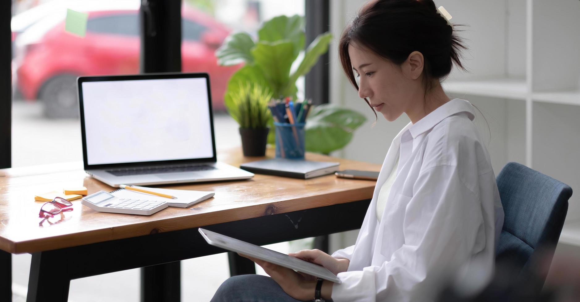 Portrait of a happy asian businesswoman working on tablet computer photo