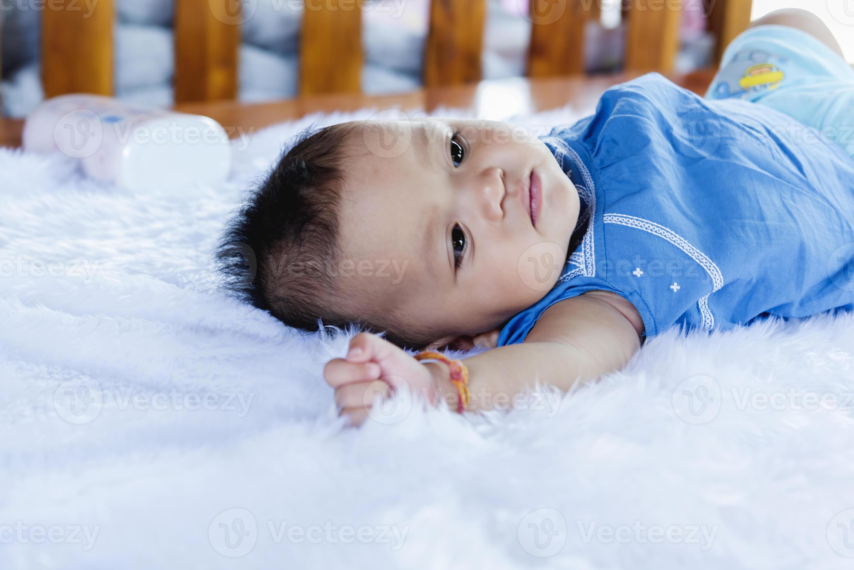 A beautiful 6 month old baby with big eyes lies on the bed. 10123618