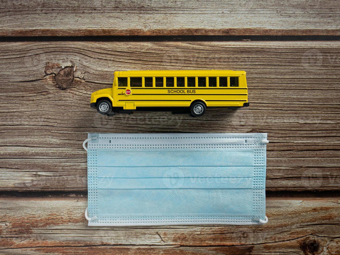 school bus and mask on wood table for education  or medical  concept photo