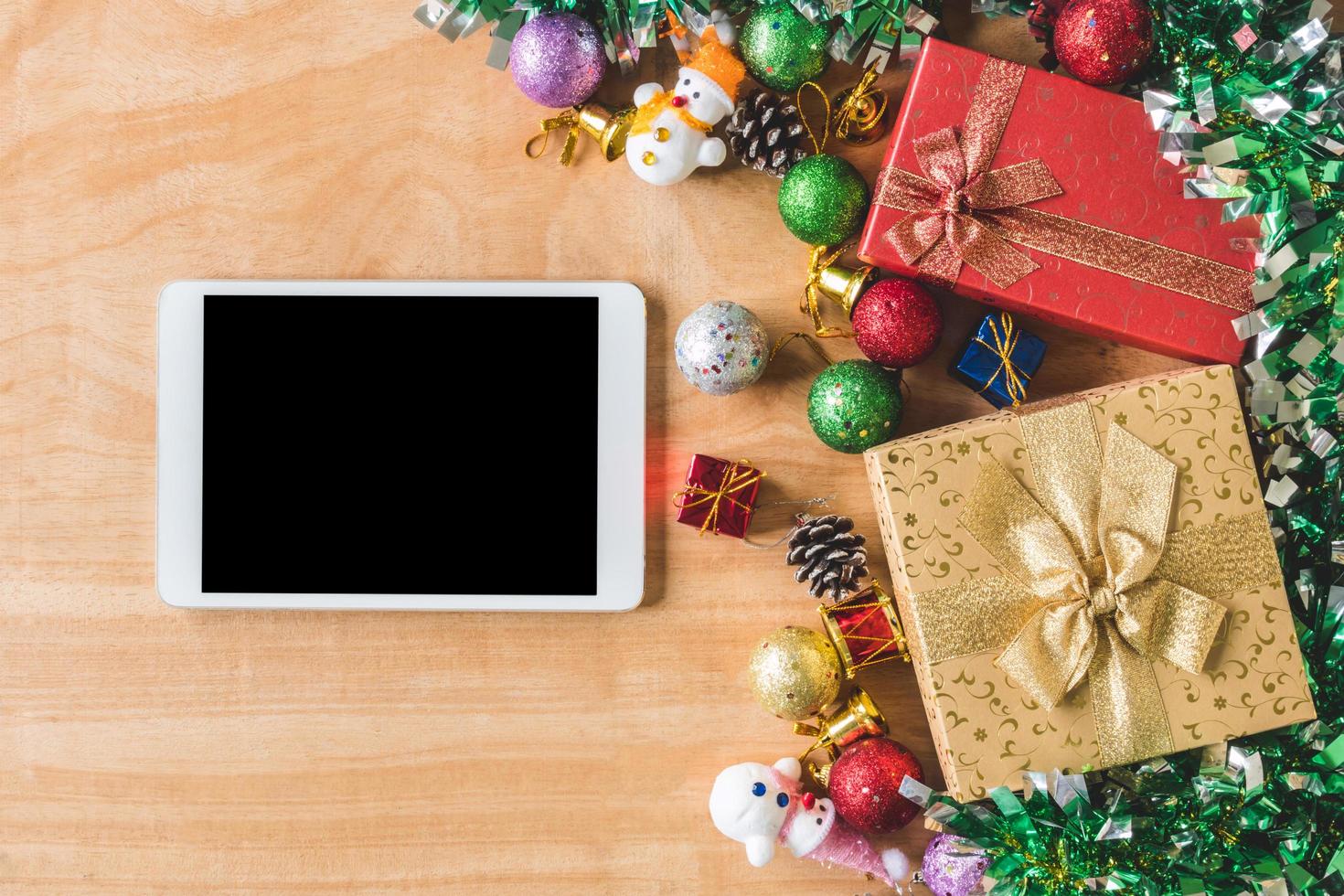 Top view of Gift boxes with Christmas decoration and Tablet on wooden table background photo