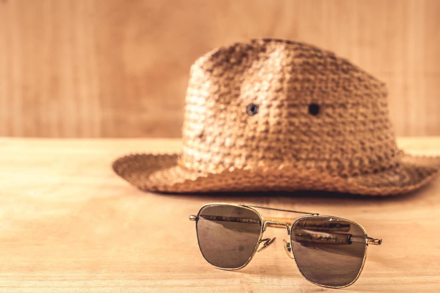 Sunglasses and hat on the wooden table photo