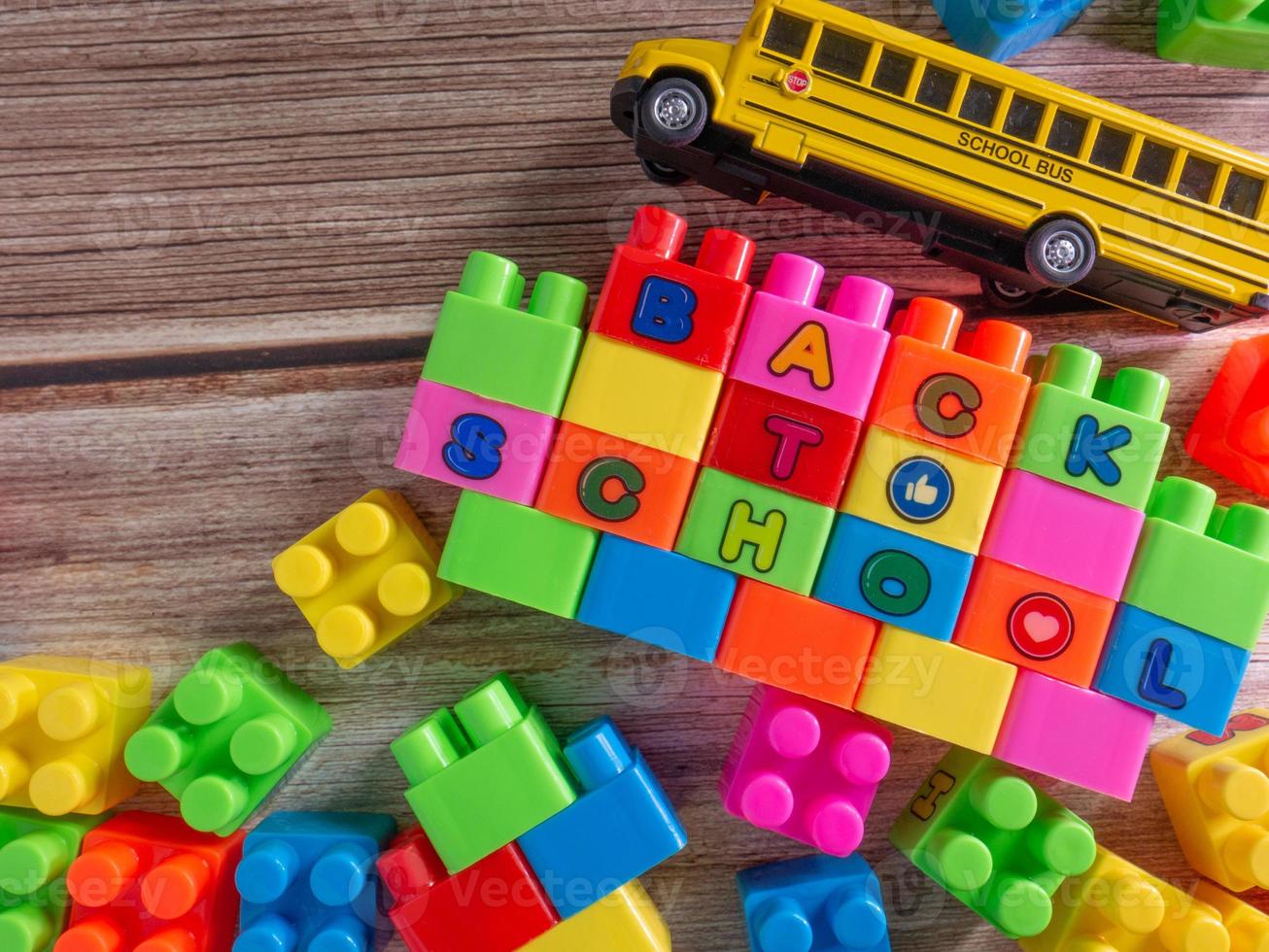 Toy brick and school bus on wood table photo