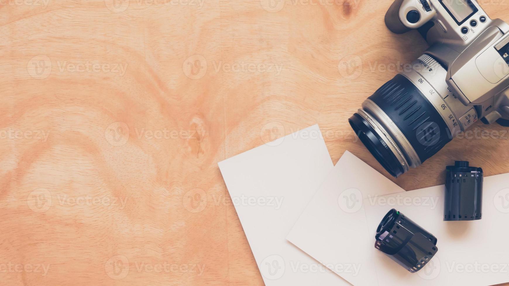 Top view of camera with film and blank postcards on wooden table background. photo