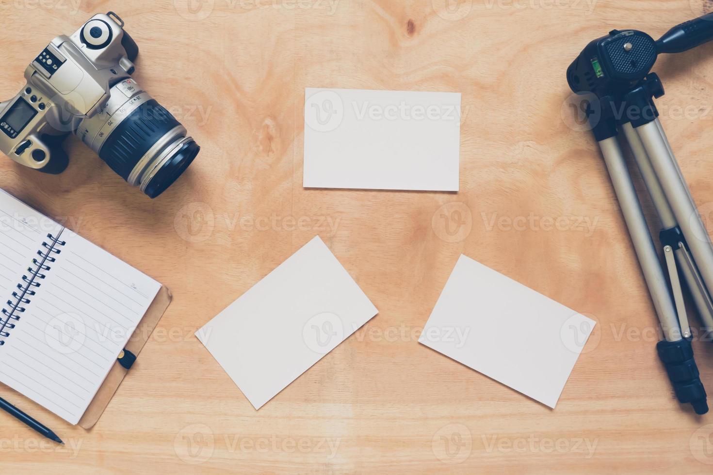 Top view of camera with tripod,notebook and blank postcard on the wooden table background. photo