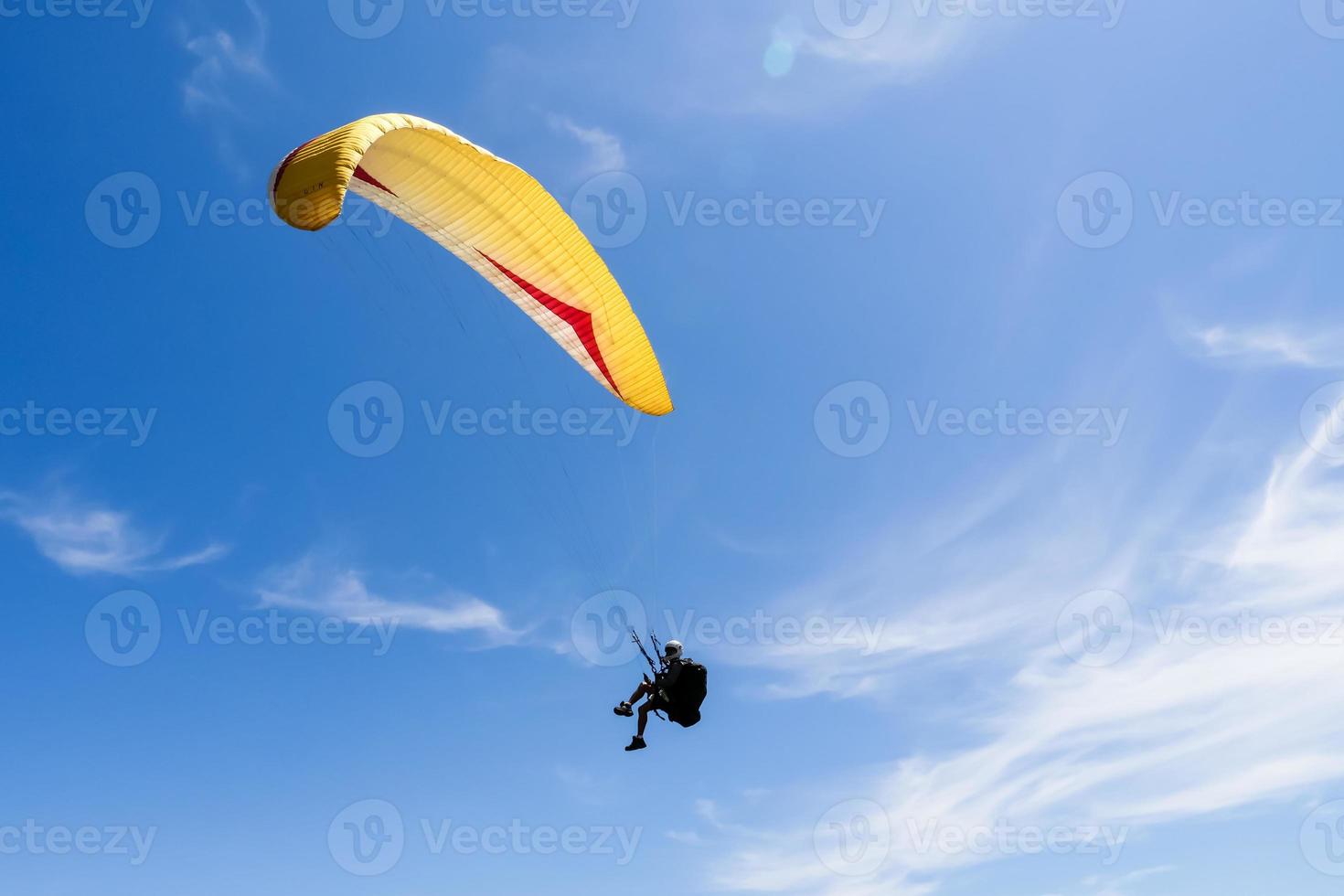 Paraglider flying in blue sky. photo