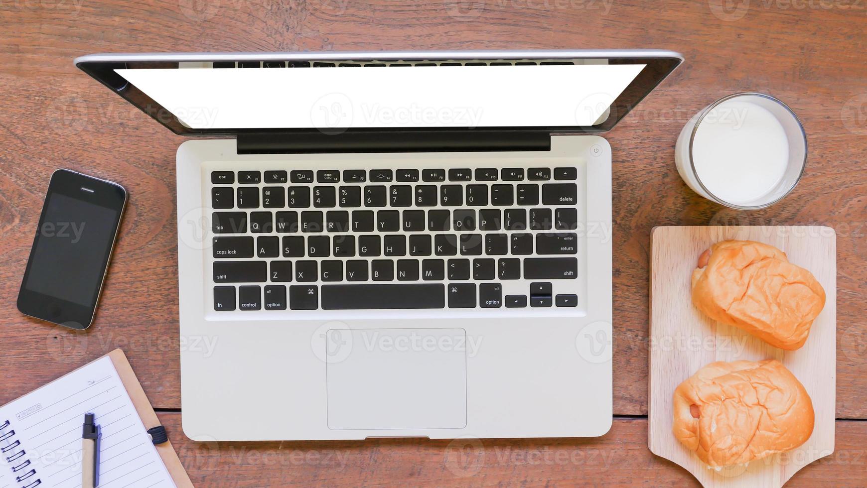 Labtop,notebook,mobile phone and breakfast on wooden table photo