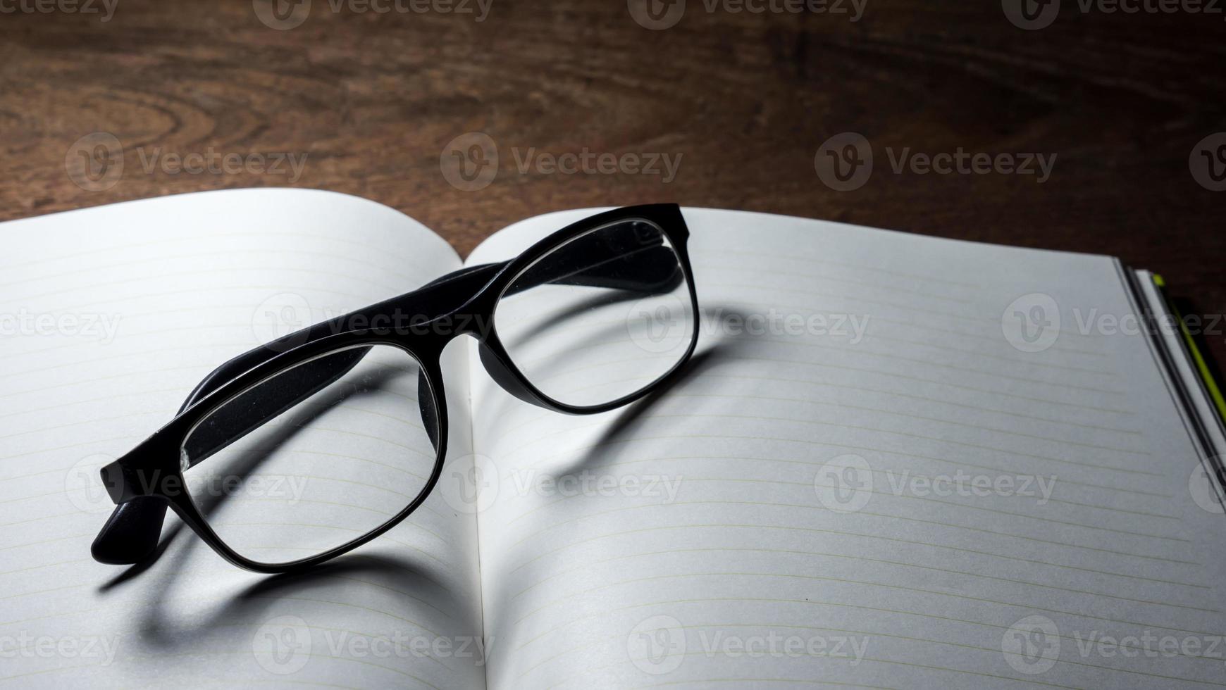 Blank notebook with  glasses on wooden table. photo