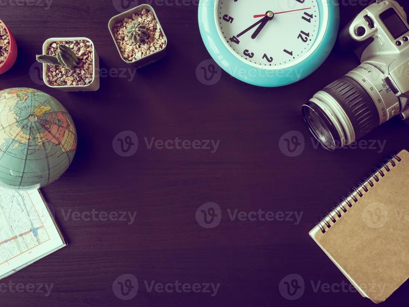 Top view of camera with cactus,map,globe,clock and notebook on the office desk.Vintage tone photo