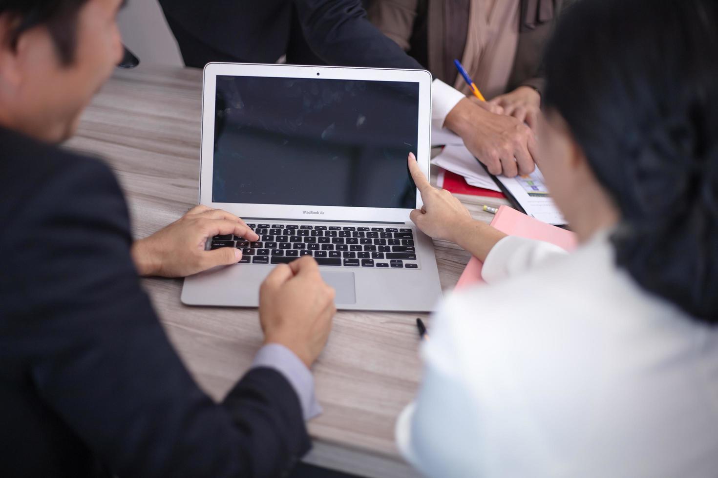 Concentrated multiethnic coworker busy using laptop brainstorm sharing thoughts at office meeting photo