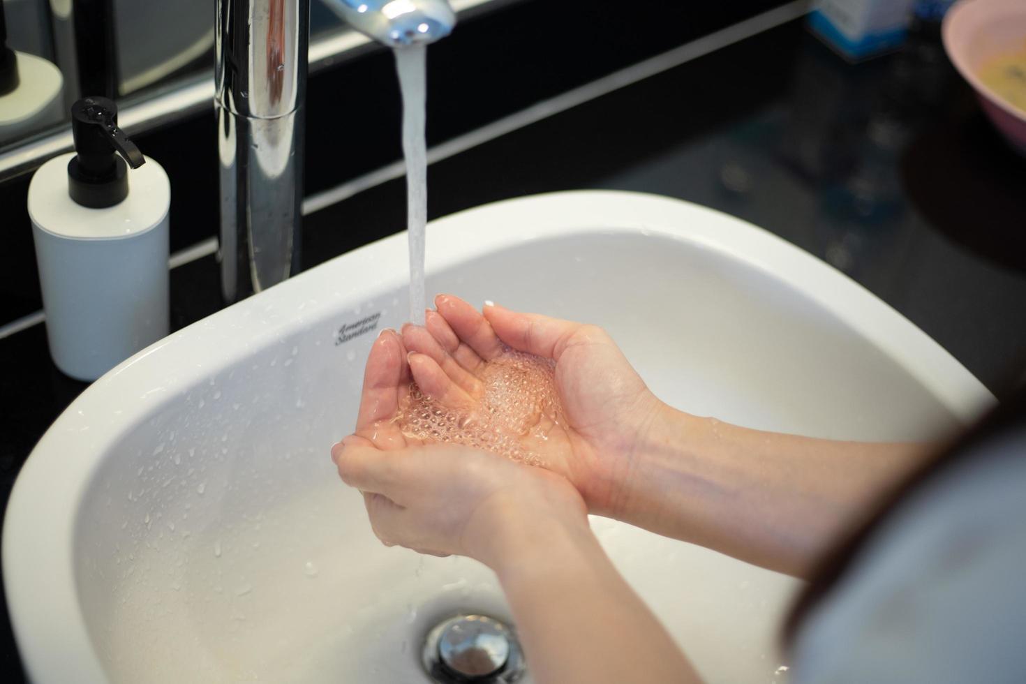 Closeup of a woman washing her hands in bathroom to prevent Covid-19 viral infection photo