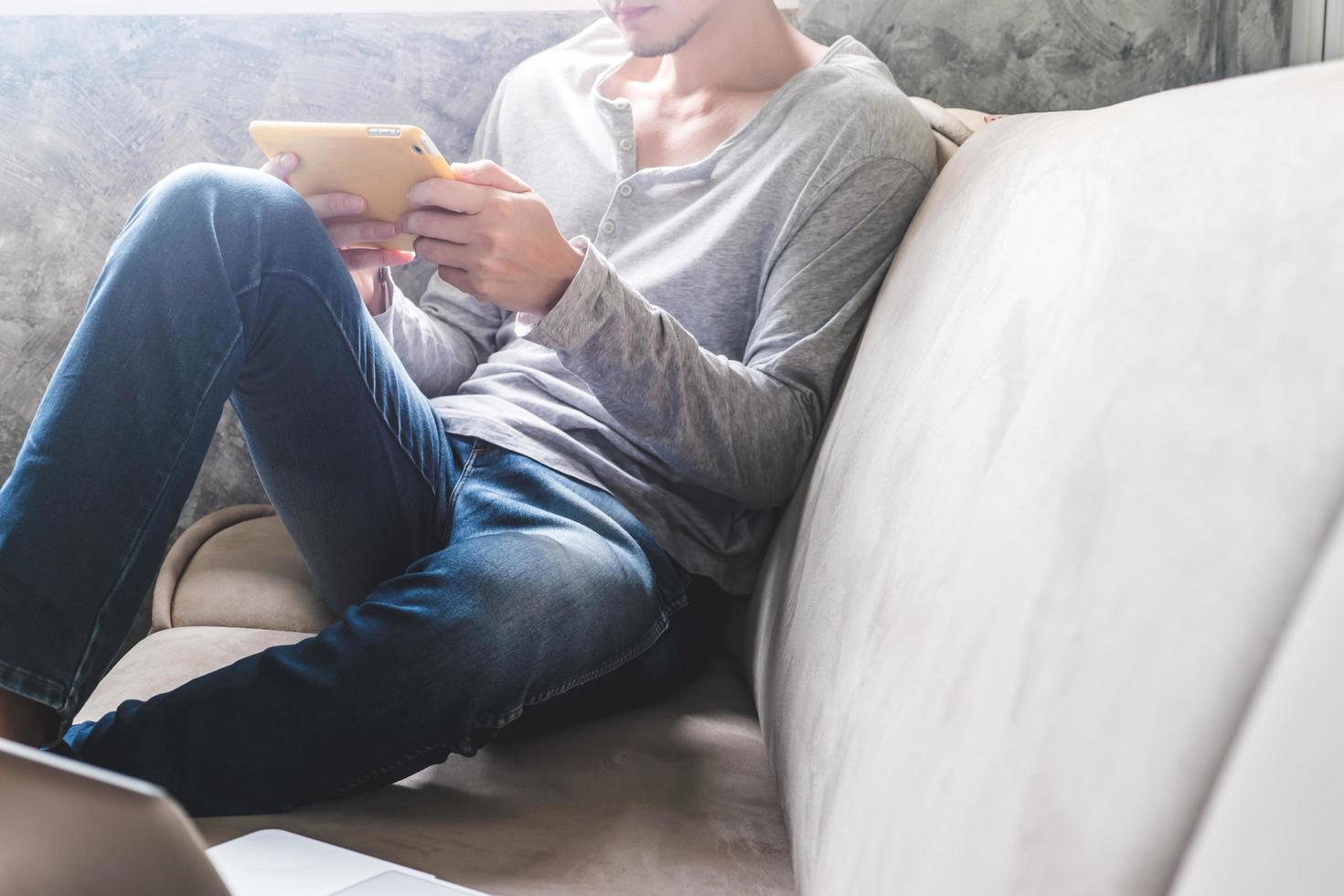 Casual young man using tablet on sofa at home. photo