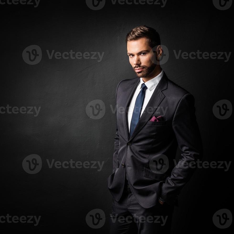Handsome young businessman standing confident on black photo