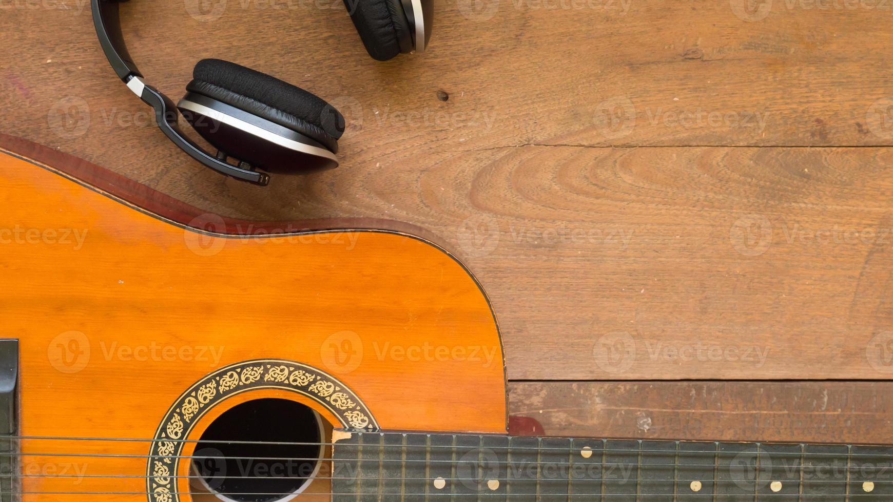 Top view workspace with headphone and acoustic guitar on wooden table background . photo
