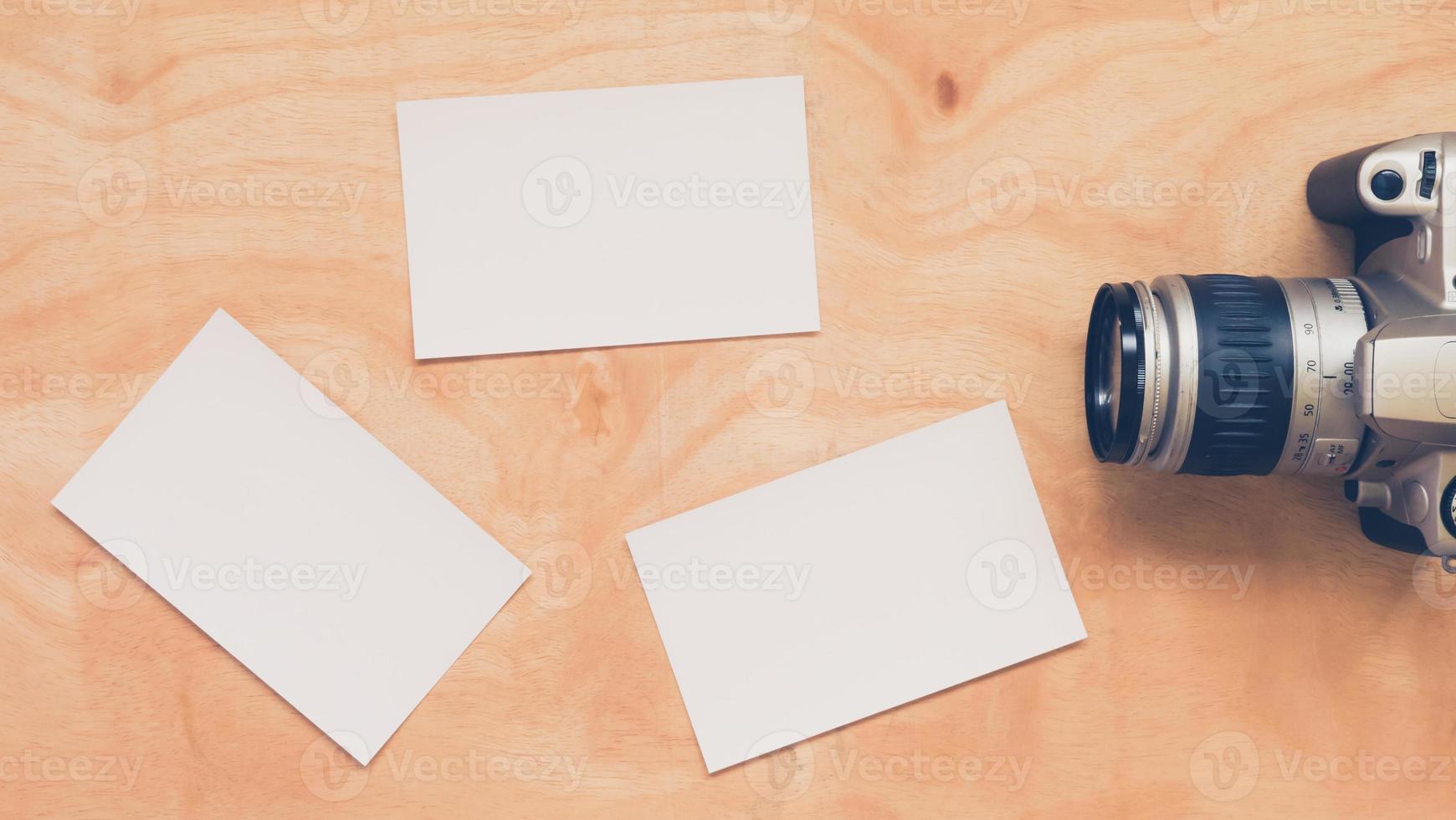 Top view of camera with blank postcards on wooden table background. photo