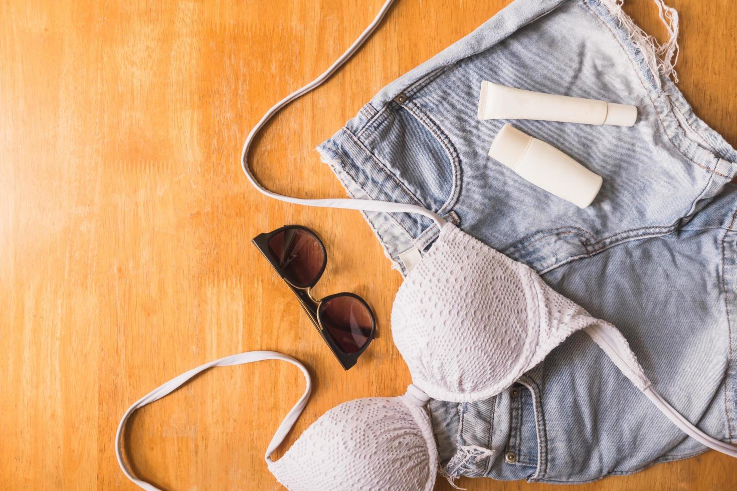 Top view of Summer clothes and accessories for woman on wooden table. Vacation concept photo