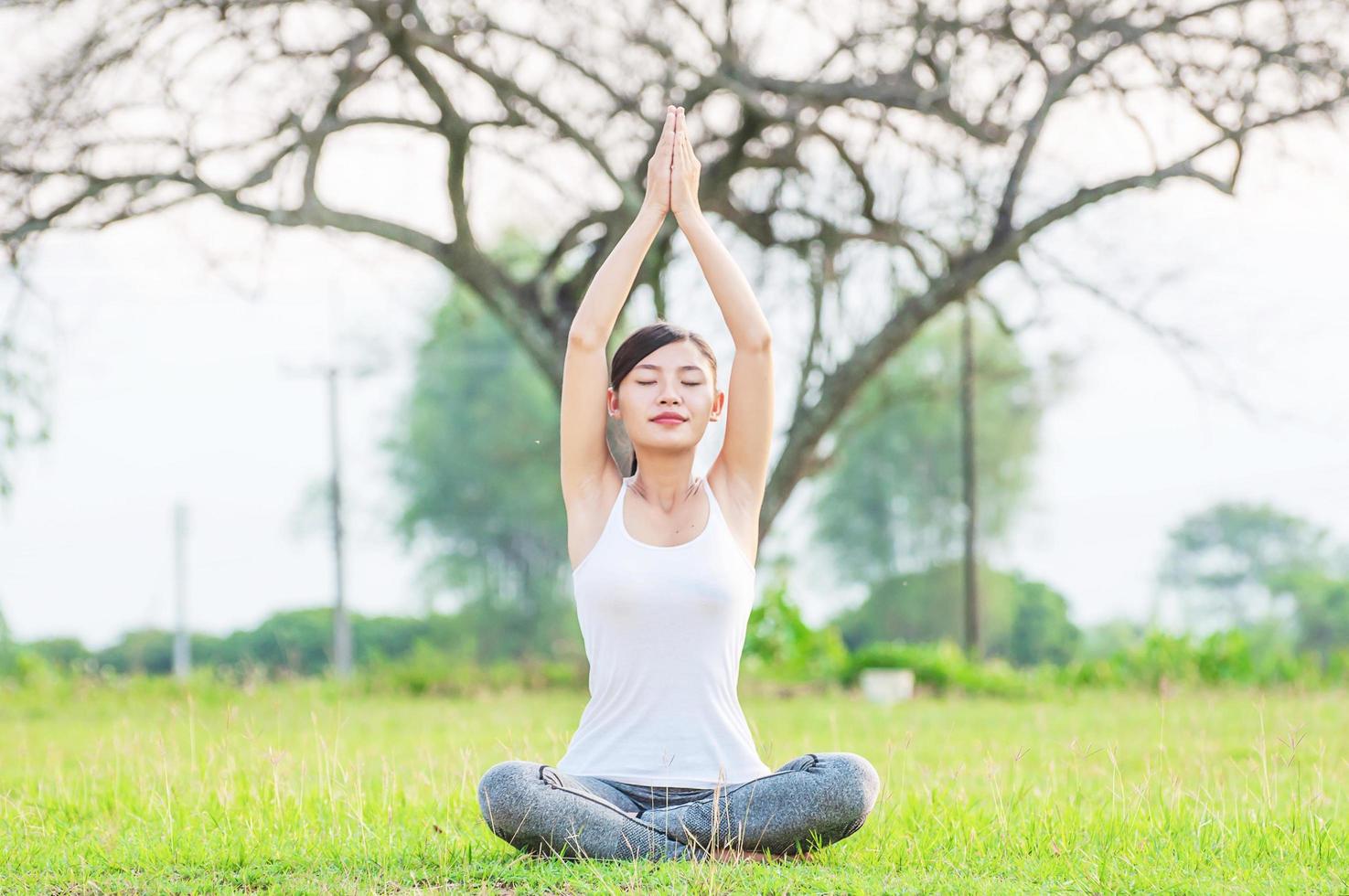 Young lady doing yoga exercise in green field outdoor area showing calm peaceful in meditation mind - people practise yoga for meditation and exercise concept photo