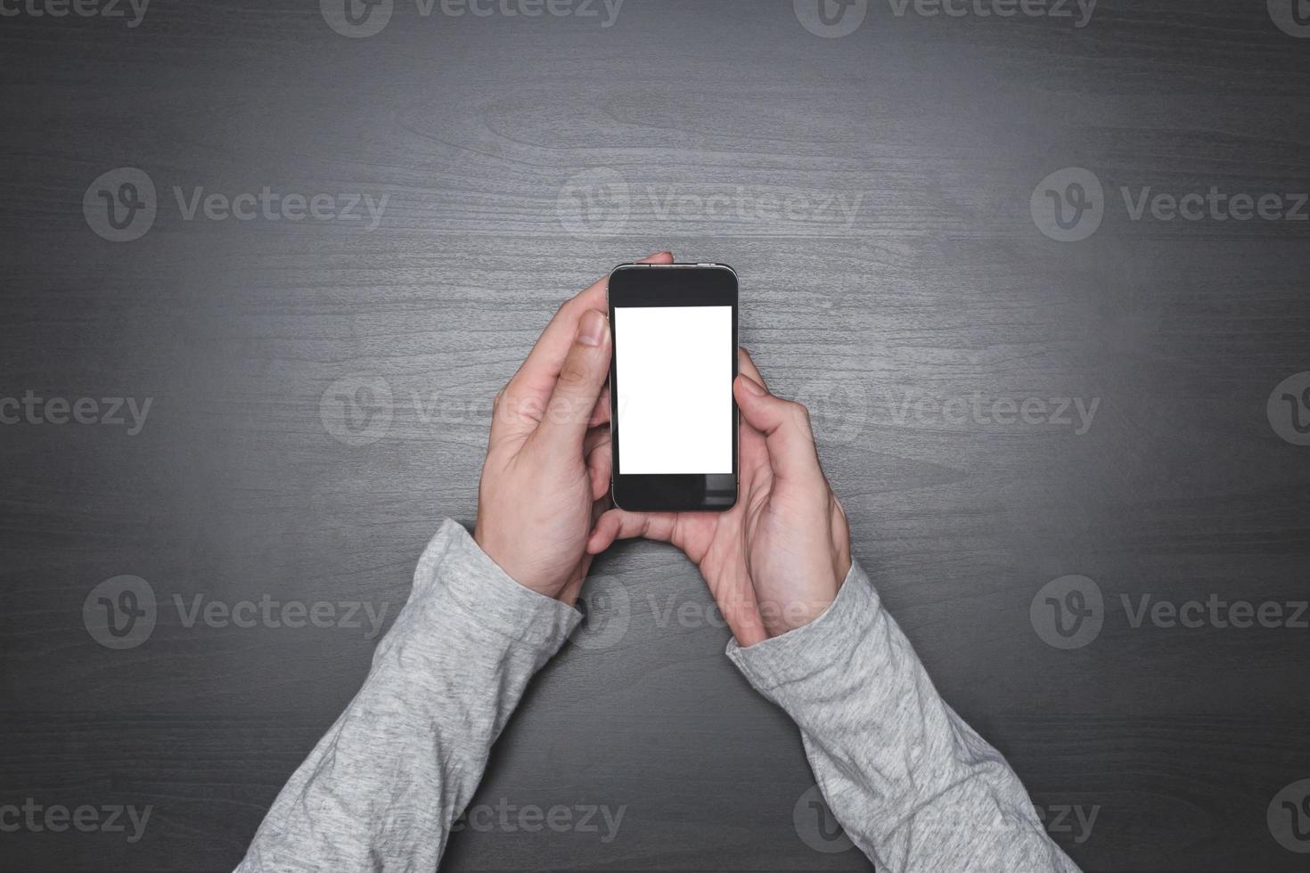 Top view of Male hands using smart phone on the black wooden desk background. photo
