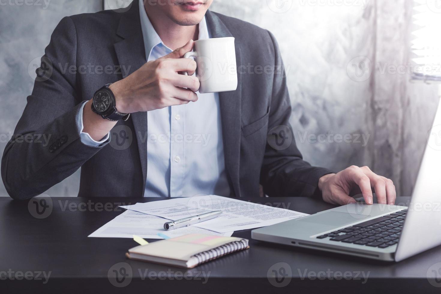 primer plano de un hombre de negocios sosteniendo una taza de café y trabajando en el escritorio de la oficina. foto