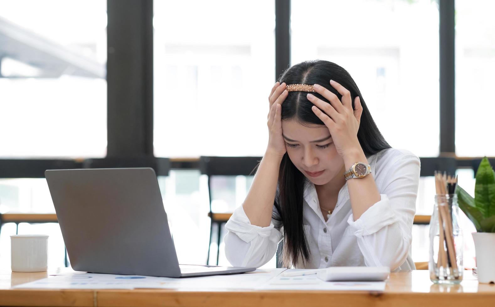 Image of an Asian business woman is stressed, bored, and overthinking from working on a tablet at the office. photo