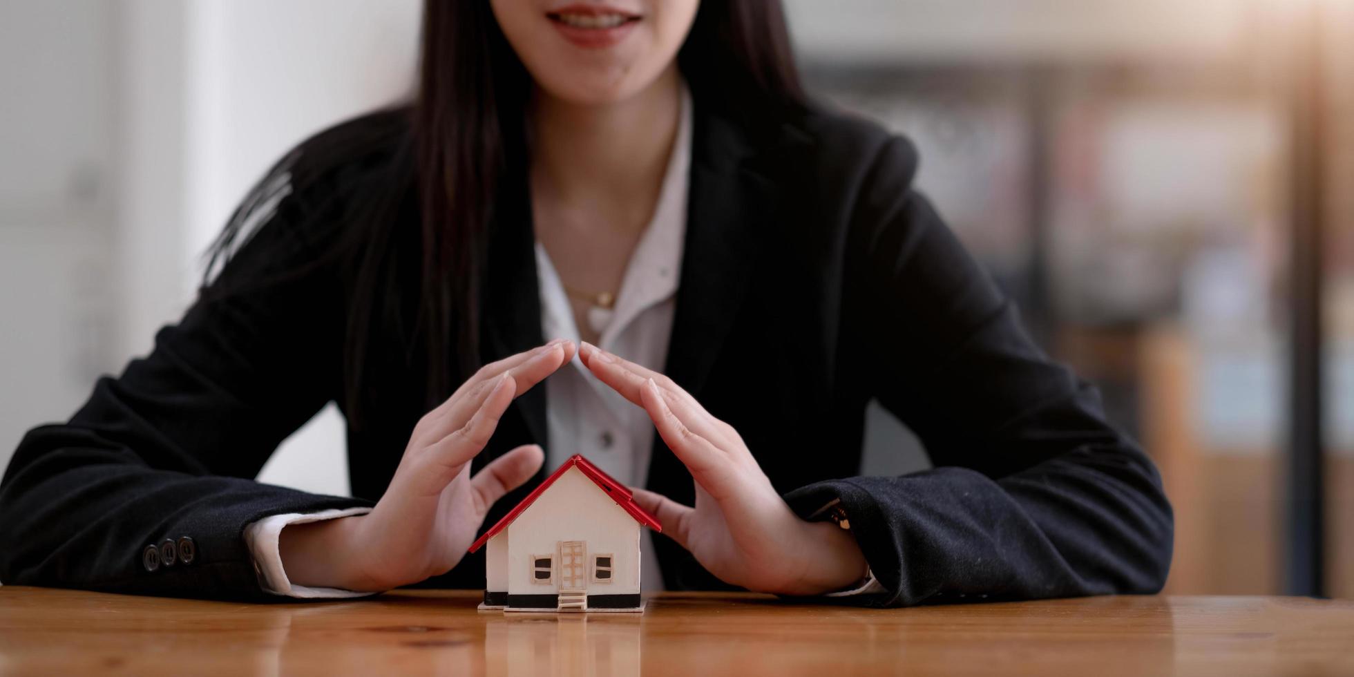 Home protection concept, close up of female hands sheltering modern house photo