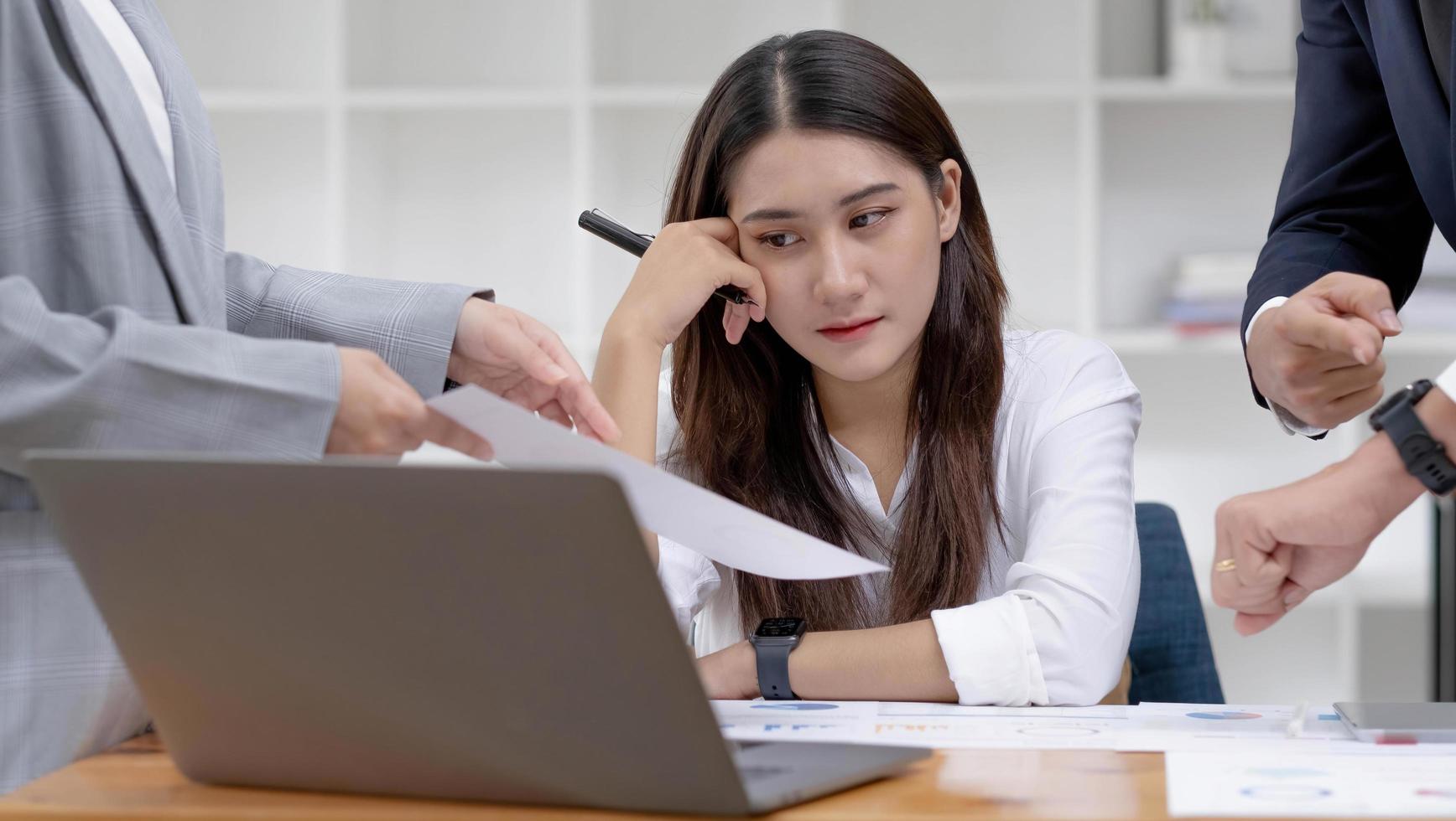 aburrida y agotada joven empresaria asiática o empleada en la seria reunión financiera con su equipo. foto